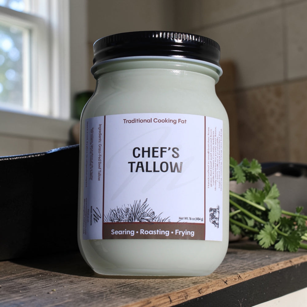 A jar of Massie Provisions Chef’s Tallow, a natural cooking fat, with a rustic label and a wooden spoon on a kitchen counter.